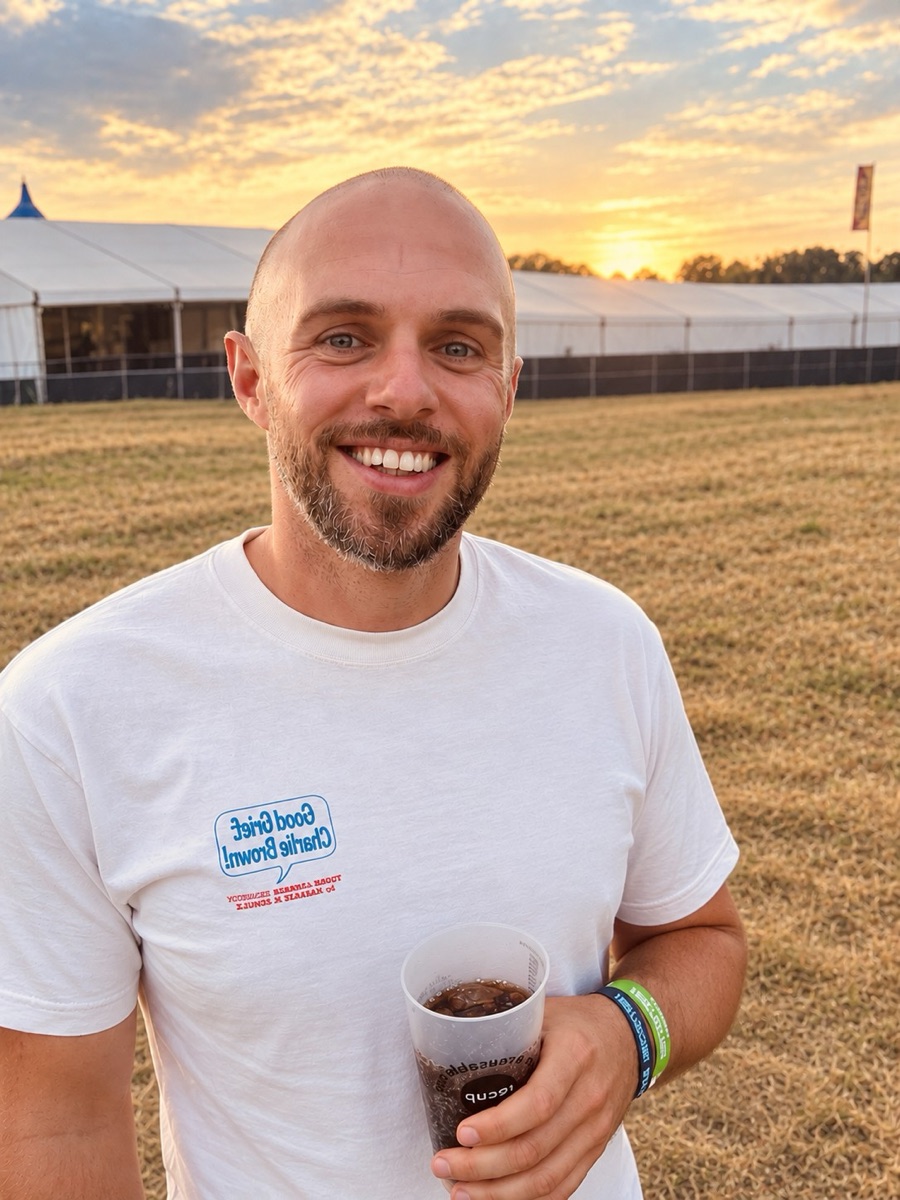 Max Ruddock smiling at a festival at sunset